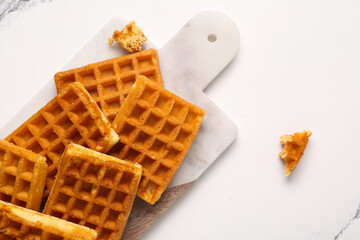 Board with tasty Belgian waffles on white background