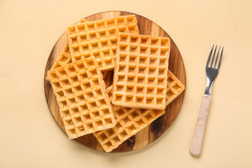 Wooden board with tasty Belgian waffles on yellow background