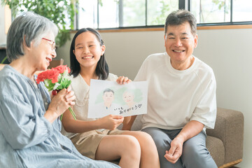 祖父母に敬老の日のお祝いに似顔絵をプレゼントする孫・女の子