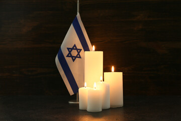 Burning candles with flag of Israel on wooden background. Day of Remembrance