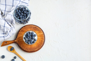 Glass of tasty yogurt with fresh blueberries on white background