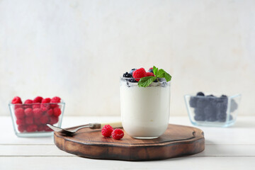 Glass of tasty yogurt with different fresh berries on white wooden background
