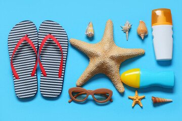 Stylish striped flip-flops with seashells, sunglasses, starfish and bottles of sunscreen cream on...