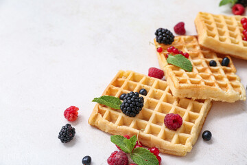 Sweet Belgian waffles with different fresh berries and mint on white background