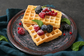 Plate of sweet Belgian waffles with different fresh berries and mint on black background