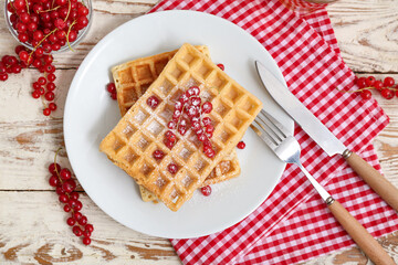 Plate of sweet Belgian waffles with fresh red currants on white wooden background