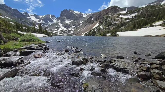 Meltwater flowing out of Lake Isabelle in Indian Peaks Wilderness, Colorado under dramatic summer cloudscape 4K.