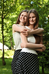Fototapeta premium Portrait of two beautiful twin sisters in park