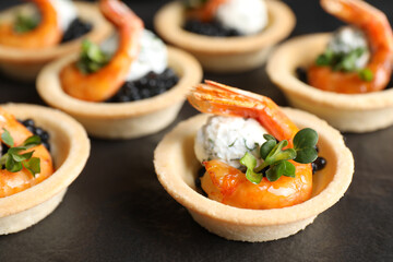 Delicious canapes with shrimps and black caviar on table, closeup