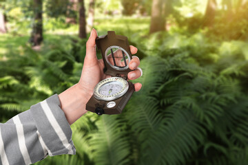 Naklejka premium Woman holding compass near fern in forest, closeup