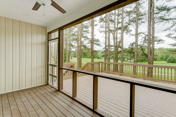 Inviting Screened-In Porch With A Ceiling Fan And Wooden Deck Overlooking Nature