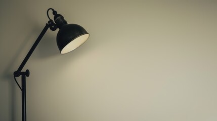 Vintage black metal desk lamp is illuminating a blank wall, creating a cozy and inviting atmosphere