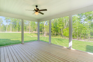 Peaceful Screened-In Porch With Ceiling Fan Overlooking Lush Backyard Greenery