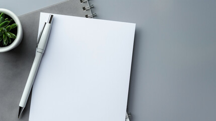 White paper and pen on gray background with space for text top down view of work area.