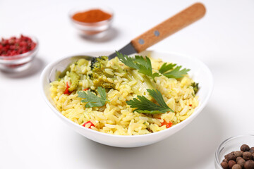 Pilaf in bowl, spices, spoon on white background, close up