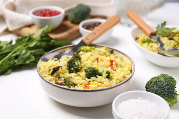 Pilaf in bowls, spices, spoons on white background, close up