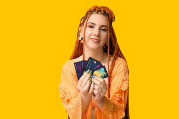Obraz premium Portrait of pretty young woman with dreadlocks and credit cards on yellow background
