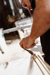 Carpenter working wood with chisel in workshop