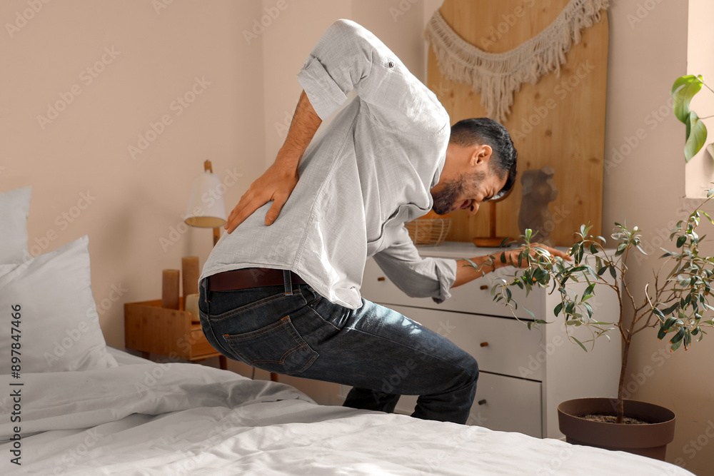 Canvas Prints Young man suffering from back pain in bedroom