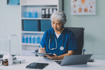 Thoughtful Hispanic female doctor sitting at her desk in a bright medical office, looking at a laptop screen.