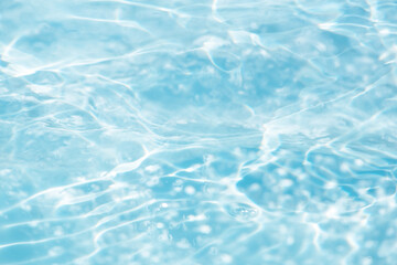Blue water with ripples on the surface. Defocus blurred transparent blue colored clear calm water surface texture with splashes and bubbles. Water waves with shining pattern texture background.