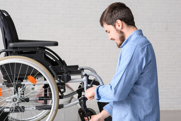 Young man repairing wheelchair on table at home