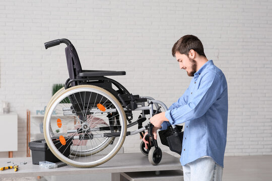 Young man repairing wheelchair on table at home - Powered by Adobe