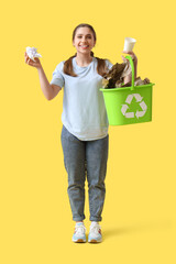 Young woman with paper garbage and recycle bin on yellow background. Waste sorting concept