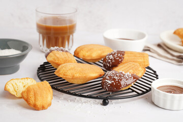 Grid of delicious madeleines and bowl of chocolate cream on white background