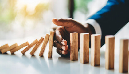 business hand halts wooden dominoes from falling over, symbolizing the prevention of a business crisis and the control of potential disruptions