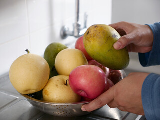 Asian muslim woman washing cleaning fruits in kitchen sink