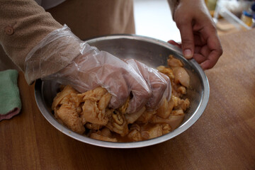 Close up of a person hand marinating chicken meat in metal bowl