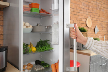Woman closing fridge in kitchen. Closeup