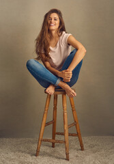 Woman, fashion and chair with happy in studio on brown background with style and swag. Female...