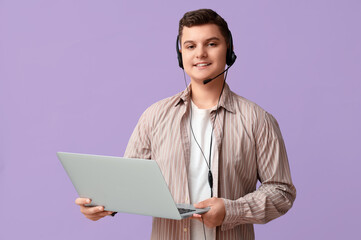 Teenage boy with headset and laptop working on lilac background