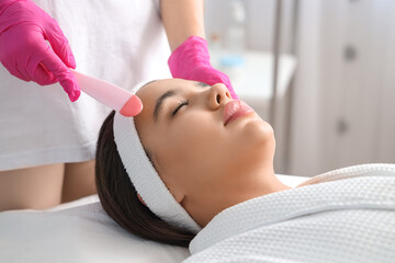 Beautician removing woman's hair on face with wax in salon, closeup