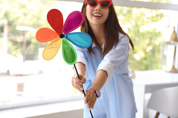Young woman in sunglasses with toy windmill at home, closeup