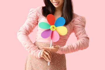Young woman with toy windmill on pink background, closeup