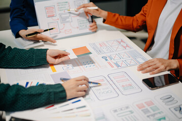 Close up view of UI developer team brainstorming on their project with laptop, smartphone and digital tablet.