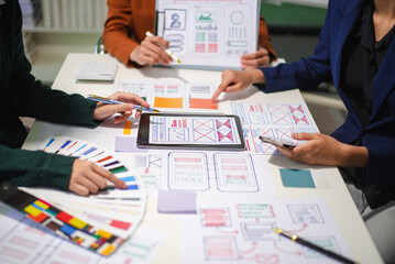 Close up view of UI developer team brainstorming on their project with laptop, smartphone and digital tablet.