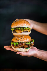 a person holding two hamburgers on top of each other