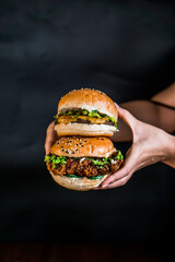a person holding two hamburgers