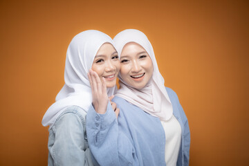Two beautiful Malaysian and Indonesian Muslim young women wearing modern and casual wear with hijab on isolated studio background. Modern hijab fashion and beauty concept