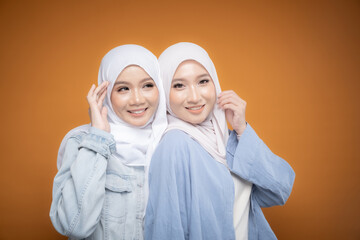 Two beautiful Malaysian and Indonesian Muslim young women wearing modern and casual wear with hijab on isolated studio background. Modern hijab fashion and beauty concept