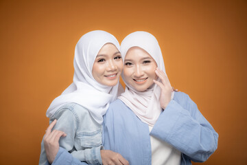 Two beautiful Malaysian and Indonesian Muslim young women wearing modern and casual wear with hijab on isolated studio background. Modern hijab fashion and beauty concept