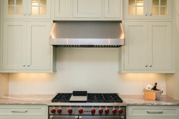 Modern Kitchen With Large Stove And Light Cabinetry Under Bright Lighting