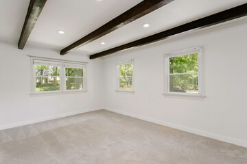 Bright Room With White Walls, Carpeted Floor, And Large Windows With Beams
