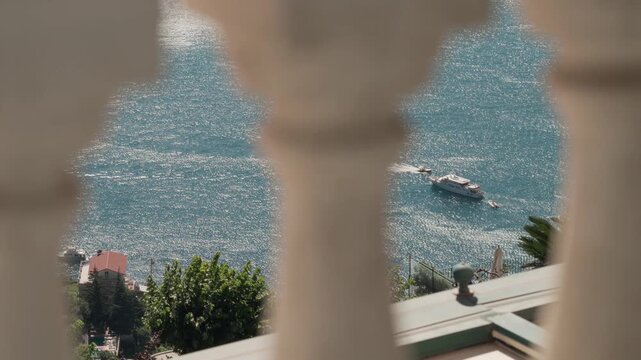 A ship floats on the Mediterranean Sea as seen through a picturesque balcony in Ravello, Italy.
