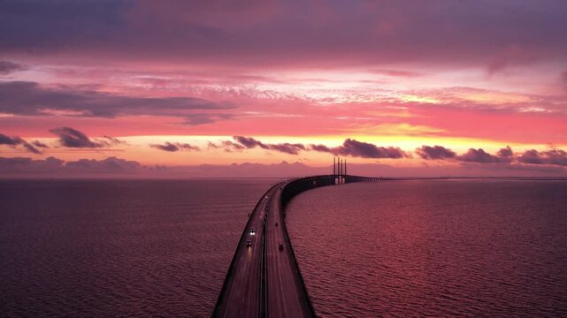 Slow  motion footage of a sunset and bridge with traffic. sky is on fire and cars a moving into the night