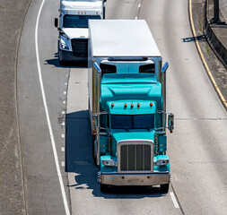 Aquamarine classic big rig semi truck with chrome accessories and roof spoiler transporting cargo...